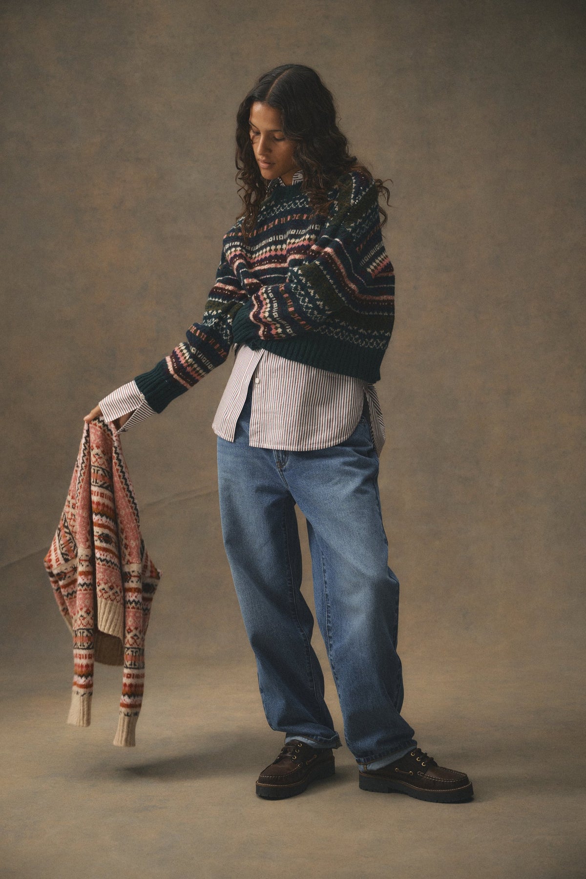 A woman in a green and red Barbour Fair Isle jumper holding a second Fair Isle knit