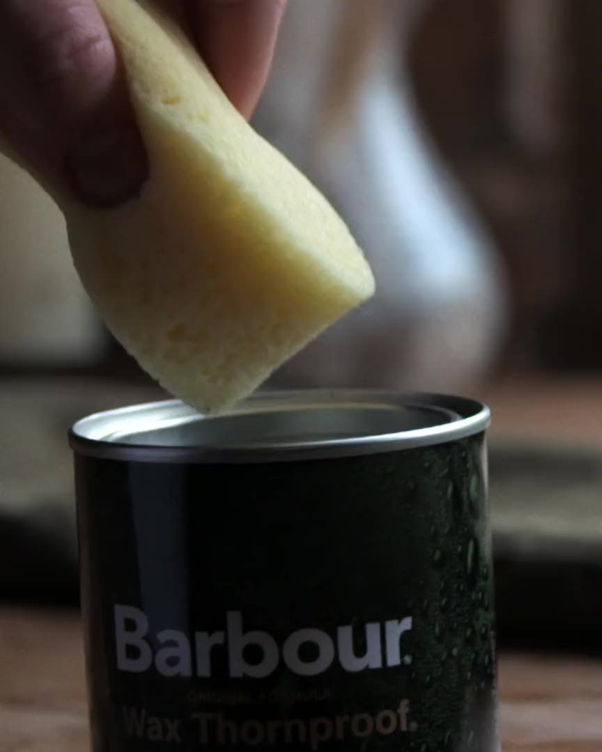 A sponge lifting wax from a tin of Barbour wax